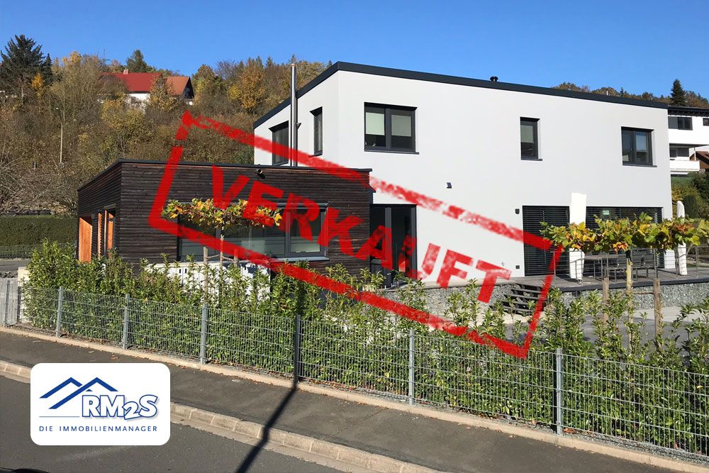 Modernes Wohnhaus mit Flachdach und dunkler Holzfassade in Hanglage