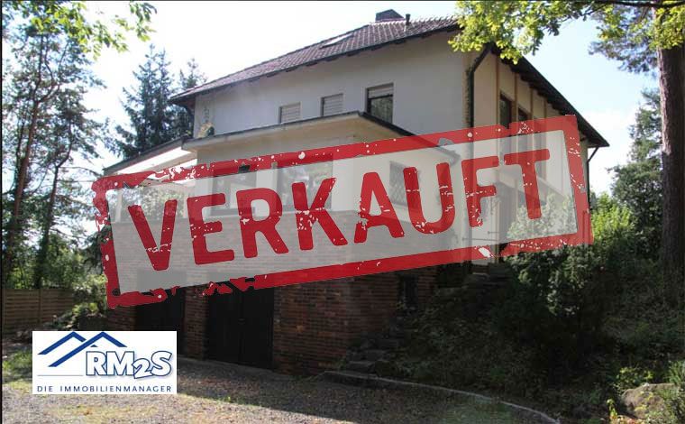 Wohnhaus mit Balkon in Hanglage, von Bäumen umgeben