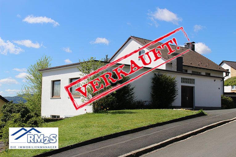 Weißes Wohnhaus an einer Straße mit angrenzender Wiese